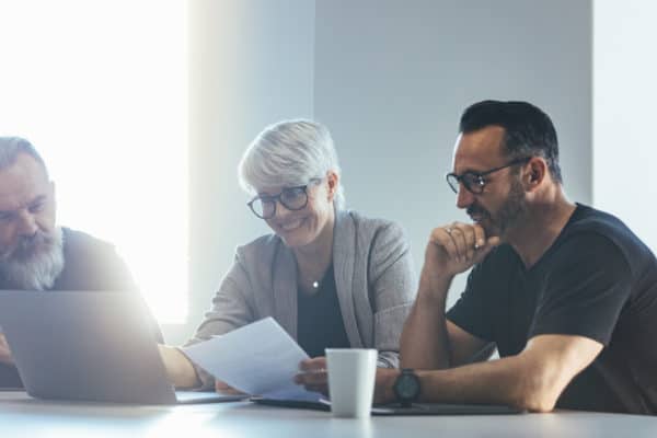 2 men and a woman are looking at a computer smiling